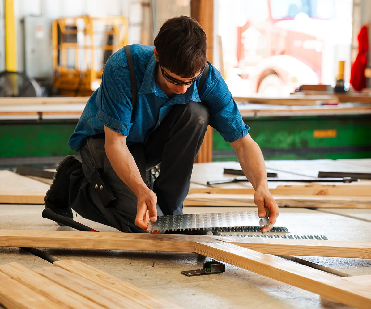 A man focused on his task, diligently assembling a truss on the floor