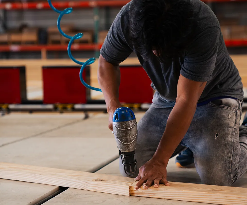 A man assembling a wooded truss on the floor